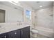 Bathroom showcasing vanity with granite countertop, a window, and a shower/tub combo with marble-patterned walls at 11598 Oak Ln, Largo, FL 33778