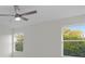 Bright bedroom featuring a ceiling fan and two windows overlooking lush green trees at 11598 Oak Ln, Largo, FL 33778