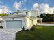 Charming two-story home showcasing a well-manicured lawn and a light blue garage door, with a delightful sky backdrop at 11598 Oak Ln, Largo, FL 33778