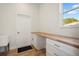 White laundry room with storage, butcher block countertop, sink, and a door to the outside at 11598 Oak Ln, Largo, FL 33778
