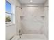 Bathroom featuring tiled shower/tub combo, a window with view, and chrome hardware and white marble pattern tiles at 11598 Oak Ln, Largo, FL 33778