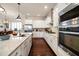 Modern kitchen with white cabinets, stainless appliances, granite countertops, and sleek hardwood flooring at 13917 Kingfisher Glen Dr, Lithia, FL 33547
