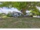Charming home with lush landscaping and mature trees, showcasing a well-maintained lawn with inviting curb appeal at 1496 Queen Anne Dr, Palm Harbor, FL 34684