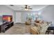 Open living room with wood-look floors, ceiling fan, palm leaf furniture, neutral paint, and mounted television at 1496 Queen Anne Dr, Palm Harbor, FL 34684