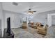 Bright living room with wood-look flooring, ceiling fan, white trim, and furniture with palm leaf accents at 1496 Queen Anne Dr, Palm Harbor, FL 34684