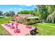 Aerial view of an outdoor patio with red tables, overlooking lush lawns and the clubhouse, ideal for gatherings at 1496 Queen Anne Dr, Palm Harbor, FL 34684