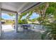 Covered outdoor patio space with a table and chairs, surrounded by lush landscaping at 1496 Queen Anne Dr, Palm Harbor, FL 34684