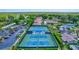 Aerial shot of tennis courts, clubhouse, pool, and a parking lot with many cars at 1496 Queen Anne Dr, Palm Harbor, FL 34684