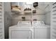 Bright laundry room with white washer/dryer, shelves, towels, and tankless hot water heater at 1726 25Th S Ave, St Petersburg, FL 33712