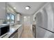 Clean white kitchen with stainless appliances, tile flooring, and a view into the adjacent living room at 2127 Scotland Dr, Clearwater, FL 33763