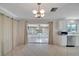 Bright living room with tile flooring, large sliding glass doors to the sun room, and white kitchen cabinets at 2127 Scotland Dr, Clearwater, FL 33763