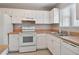 Well-lit kitchen features white cabinets, matching appliances, tile floors, and a stainless steel sink at 2934 Lichen Ln # A, Clearwater, FL 33760
