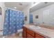 Cozy bathroom featuring a vanity with a granite top, toilet and shower with blue floral shower curtain at 30475 Satinleaf Run, Brooksville, FL 34602