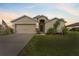 Twilight view of a single-story home with a manicured lawn, two car garage, and an inviting front entrance at 30475 Satinleaf Run, Brooksville, FL 34602