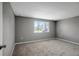 Spacious bedroom featuring plush gray carpet and a bright window for natural light at 4111 Stratfield Dr, New Port Richey, FL 34652