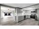 Bright kitchen with gray cabinets, stainless steel appliances, and a view into the living room with a fireplace at 4111 Stratfield Dr, New Port Richey, FL 34652