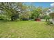 Wide open backyard area with room to enjoy the outdoors, mature trees and red shed at 6231 Massey Rd, Zephyrhills, FL 33542
