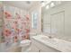 Bright bathroom with floral shower curtain, and vanity with marble countertop at 6231 Massey Rd, Zephyrhills, FL 33542