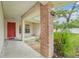 Home entry featuring a bright red front door, column and tropical greenery at 6231 Massey Rd, Zephyrhills, FL 33542