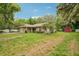 Property with well-manicured lawn, mature trees, attached garage, and red storage shed at 6231 Massey Rd, Zephyrhills, FL 33542