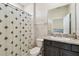 Well-lit bathroom features a shower with patterned curtain and vanity with granite countertop at 6674 Cobble Bliss St, Zephyrhills, FL 33541