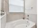 Bright bathroom bathtub with tiled walls and a window letting in natural light at 6674 Cobble Bliss St, Zephyrhills, FL 33541