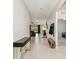 Hallway featuring neutral tile floors, coat rack and decorative table, leading to living areas and bedrooms at 6674 Cobble Bliss St, Zephyrhills, FL 33541