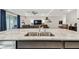 Kitchen island features a large stainless steel sink, granite counter tops and views of the open concept living area at 6674 Cobble Bliss St, Zephyrhills, FL 33541