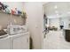 Functional laundry room with washer, dryer, and shelving, plus an open view into the kitchen at 6674 Cobble Bliss St, Zephyrhills, FL 33541