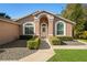 Inviting home entrance with arched doorway, manicured hedges, and lovely landscaping at 775 Brittany Park Blvd, Tarpon Springs, FL 34689