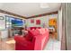Comfortable living room featuring a red sofa, TV, doorway to a bedroom, and decorative accents at 8215 Hixton Dr, Port Richey, FL 34668