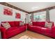 Bright living room with red sofas, floral accents, and natural light from the sliding glass door at 8215 Hixton Dr, Port Richey, FL 34668