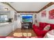 Cozy living room featuring vibrant red sofa, wood-look flooring, adjacent to the breakfast bar, and a large TV screen at 8215 Hixton Dr, Port Richey, FL 34668