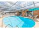 Enclosed pool area featuring clear blue water, patio furniture, and a covered seating area at 8215 Hixton Dr, Port Richey, FL 34668