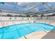 A crystal clear pool with surrounding stone pavers, a screened lanai, and a manicured yard at 8215 Hixton Dr, Port Richey, FL 34668