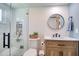 Bright bathroom featuring a glass shower, modern vanity, and stylish round mirror and shiplap walls at 8326 Archwood Cir, Tampa, FL 33615