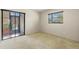 Bright bedroom with carpet, two windows, and sliding glass door to the balcony at 10 James Ct, Oldsmar, FL 34677