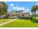 Well-maintained single-story home with a green lawn, a picket fence, and a red front door at 10 James Ct, Oldsmar, FL 34677