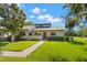 Charming single-story home featuring a well-manicured lawn, a red door, and a light gray exterior at 10 James Ct, Oldsmar, FL 34677