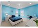 Stylish bedroom with a plush bed, and a bright blue accent wall with lots of natural light at 10007 Hazelnut Ct, Tampa, FL 33647
