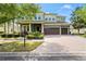Stately two-story home featuring a three-car garage, well-manicured lawn, and mature trees at 10007 Hazelnut Ct, Tampa, FL 33647