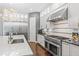 A modern kitchen features a stainless steel Viking range, quartz counters, and stylish gray and white cabinets at 10007 Hazelnut Ct, Tampa, FL 33647
