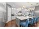 Modern kitchen with white cabinets, an island with blue chairs, and unique light fixtures, perfect for entertaining at 10007 Hazelnut Ct, Tampa, FL 33647
