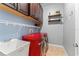 Functional laundry room with modern red washer/dryer, built-in cabinets, sink, and practical shelving at 10007 Hazelnut Ct, Tampa, FL 33647