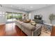 A bright living room with a large couch, wood floors, a tv, and views to an outdoor patio and pool at 10007 Hazelnut Ct, Tampa, FL 33647
