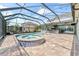 Backyard pool with attached jacuzzi, patio, and an outdoor kitchen under a screened enclosure at 10007 Hazelnut Ct, Tampa, FL 33647