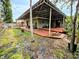A house with a large wooden deck, surrounding trees, and a grassy yard at 103 1St St, Belleair Beach, FL 33786