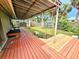 A house with a large wooden deck, surrounding trees, and a grassy yard at 103 1St St, Belleair Beach, FL 33786