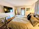 Comfortable primary bedroom with hardwood floors, soft lighting, and mounted flat screen TV at 103 1St St, Belleair Beach, FL 33786