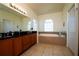Bright bathroom with double sinks, large vanity mirror, bathtub, and tile floors at 10400 Golden Ave, Weeki Wachee, FL 34613